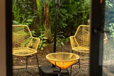 three wicker chairs and a table in a garden at Suwa Villa Arenal in Fortuna