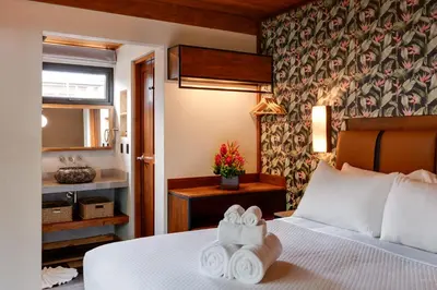 a hotel room with a bed with towels on it at Suwa Villa Arenal in Fortuna