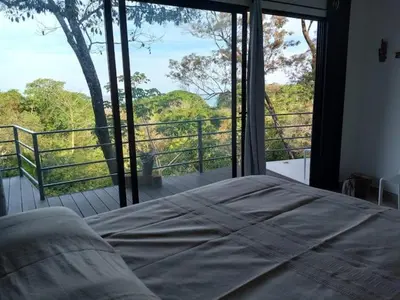 a bedroom with a bed in front of a large window at Laurel Jungle & Ocean in Santa Teresa Beach