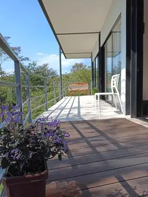 a porch of a house with a chair and flowers at Laurel Jungle & Ocean in Santa Teresa Beach