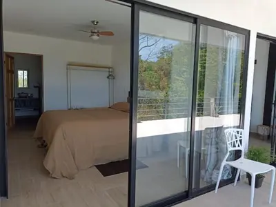 a bedroom with a bed and a sliding glass door at Laurel Jungle & Ocean in Santa Teresa Beach
