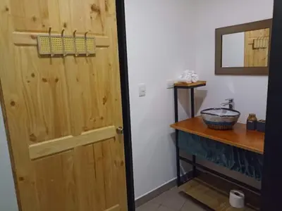 a bathroom with a wooden door and a sink at Laurel Jungle & Ocean in Santa Teresa Beach
