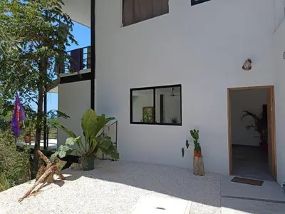 a white building with some plants and a doorway at Laurel Jungle & Ocean in Santa Teresa Beach