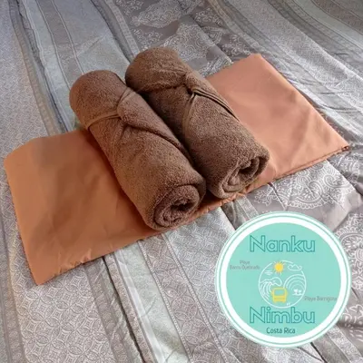 a pair of towels sitting on top of a bed at Nanku Nimbu Casa-Bus equipada cerca de playas in Sámara