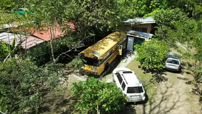 a yellow bus and a white car parked in a lot at Nanku Nimbu Casa-Bus equipada cerca de playas in Sámara