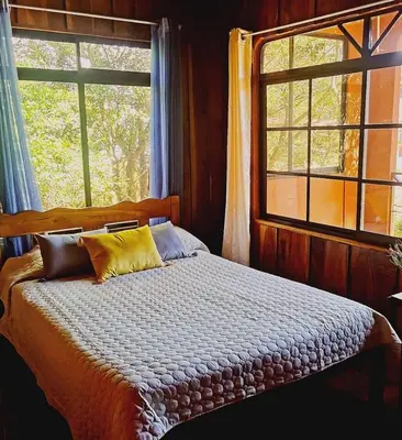a bed in a room with two windows and a bed sidx sidx sidx at Villa El Nido Monteverde in Monteverde Costa Rica