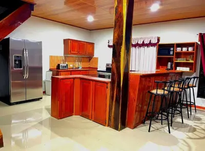 a kitchen with wooden cabinets and a stainless steel refrigerator at Villa El Nido Monteverde in Monteverde Costa Rica