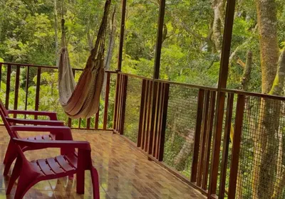 a porch with two chairs and a hammock on it at Villa El Nido Monteverde in Monteverde Costa Rica