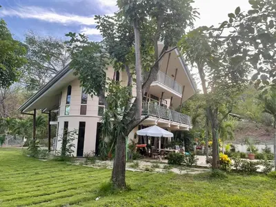 a large white house with a balcony and trees at Villa Pura Vida in Matapalo
