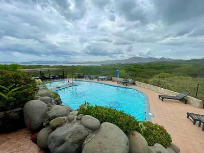 a swimming pool with a rock wall around it at Villa Pura Vida in Matapalo