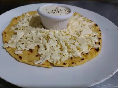 a white plate with a pizza with cheese on it at El Valle Mineral Springs in San Ramón