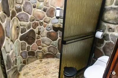 a stone bathroom with a toilet and a stone wall at El Valle Mineral Springs in San Ramón