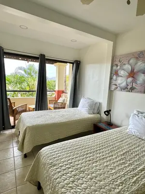 a hotel room with two beds and a balcony at Rooftop Sunset Cove in Liberia