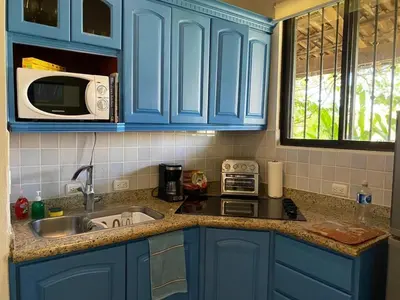 a kitchen with blue cabinets and a sink and a microwave at Turtle's Nest Condo in Liberia
