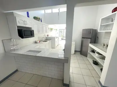 a kitchen with white cabinets and a refrigerator at 3 Min from SJO airport Kaeli in Alajuela City