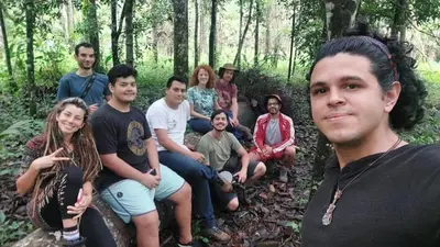a group of people sitting on a log in the woods at Finca Bambú Del Valle in Santa Clara