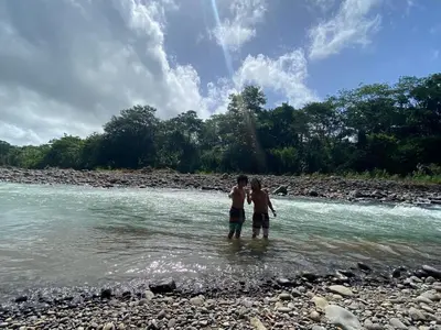 two men standing in the water on a river at Finca Bambú Del Valle in Santa Clara