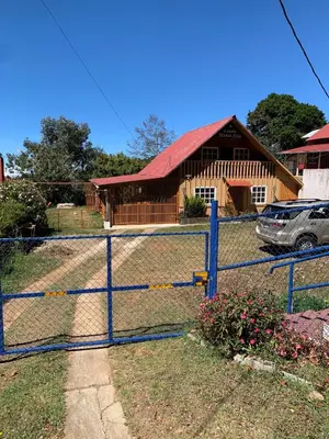 a fence in front of a house with a building at Cabaña Mamá Elia in Trinidad