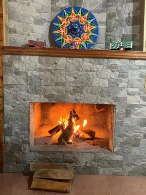 a stone fireplace with a fire in it at Cabaña Mamá Elia in Trinidad