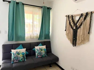 a couch in a living room with green curtains at Cocomarindo Breeze Condo and Amazing Pool in Coco