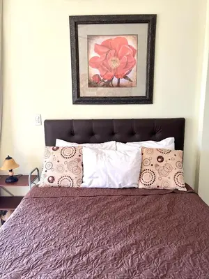 a bedroom with a bed with a flower painting on the wall at Oceanview Rancho with Two bedroom & Two baths in Coco