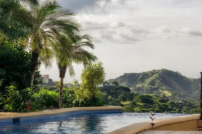 a swimming pool with palm trees and a mountain at Casa Blanca Two Bedroom,Two Bath Oceanview Condo in Coco