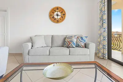 a living room with a couch and a clock on the wall at Casa Blanca Two Bedroom,Two Bath Oceanview Condo in Coco