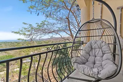 a swing on a balcony with a view of the ocean at Casa Blanca Two Bedroom,Two Bath Oceanview Condo in Coco