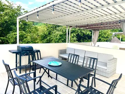 a patio with a table and chairs under a pergola at Sunny Tropical condo and rooftop terrace in Coco