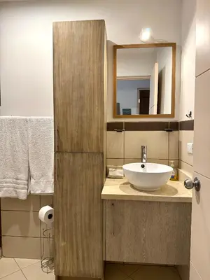 a bathroom with a sink and a mirror at Parakeet Paradise 2nd floor Condo with Rooftop in Coco