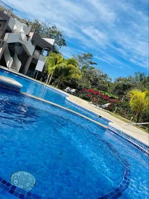 a large blue swimming pool in front of a building at Parakeet Paradise 2nd floor Condo with Rooftop in Coco