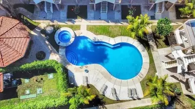 an overhead view of a swimming pool in front of a house at Parakeet Paradise 2nd floor Condo with Rooftop in Coco