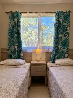 two beds in a room with a window at Parakeet Paradise 2nd floor Condo with Rooftop in Coco