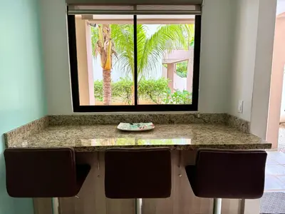 a kitchen counter with a window and two chairs at EndlessSummer Beach Escape in Coco