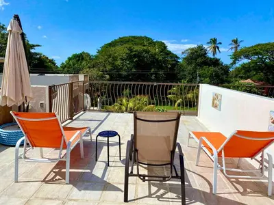 a patio with three chairs and an umbrella at Sun and Waves Getaway in Coco
