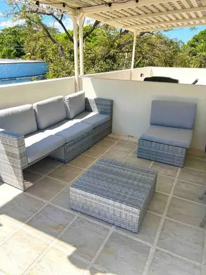 a patio with a couch and a chair and an umbrella at Discounted - PuraVida Escape and rooftop terrace in Coco