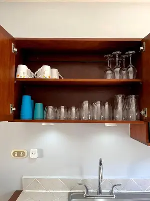 a kitchen with a sink and shelves with glass dishes at Sea Bottom Ground Condo in Coco