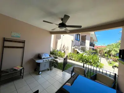 a living room with a ceiling fan and a balcony at Sea Bottom Ground Condo in Coco