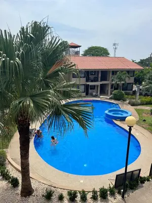 a swimming pool with a palm tree in front of a building at Coral Reef Condo in Coco