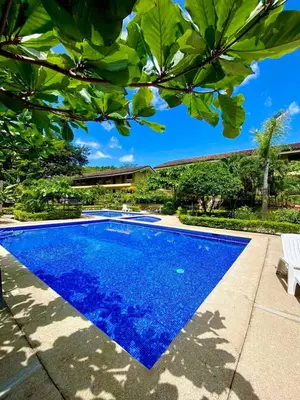 a blue swimming pool in a yard with trees at Cabaña en el Sol Cabin in the Sun in Ocotal