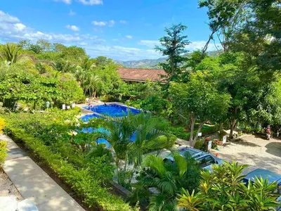 a resort with a swimming pool in a garden at Cabaña en el Sol Cabin in the Sun in Ocotal