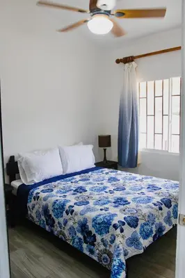 a bedroom with a blue and white bed with a ceiling fan at Discounted - Hermosa Paradise Mins from beach in Playa Hermosa