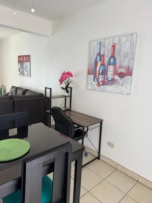 a living room with a table and a painting of wine bottles at Charming Condo Orchidea in Coco
