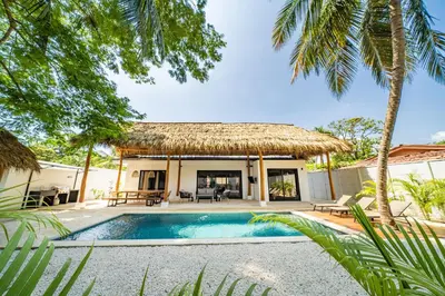 a villa with a swimming pool and a thatch roof at Tropical brand new 4 BR gem in Potrero near beach - Casa Marzo in Potrero
