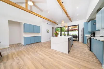 an open kitchen with blue cabinets and a wooden floor at Tropical brand new 4 BR gem in Potrero near beach - Casa Marzo in Potrero