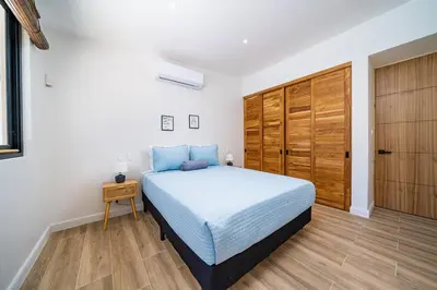 a bedroom with a bed and a wooden closet at Tropical brand new 4 BR gem in Potrero near beach - Casa Marzo in Potrero