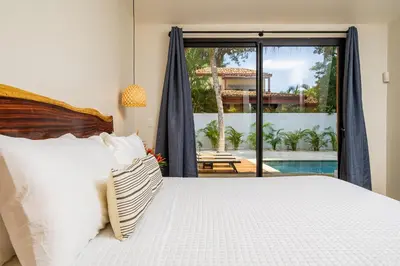 a bedroom with a bed and a view of a pool at Tropical brand new 4 BR gem in Potrero near beach - Casa Marzo in Potrero