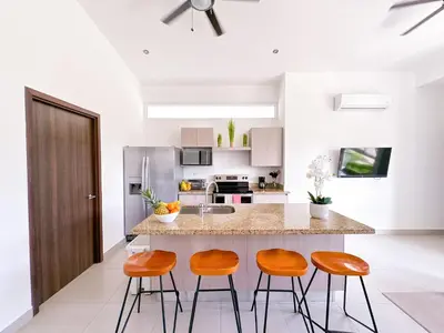 a kitchen with a island with three bar stools at Pura Vida Apartment with nice pool walking distance to the heart of Jaco in Jacó