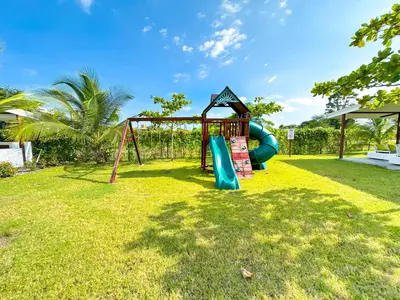 a playground with a slide in the grass at Pura Vida Apartment with nice pool walking distance to the heart of Jaco in Jacó