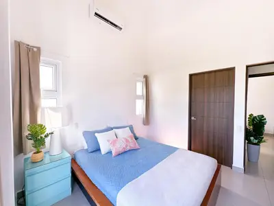 a bedroom with a bed with blue sheets and a wooden cabinet at Pura Vida Apartment with nice pool walking distance to the heart of Jaco in Jacó